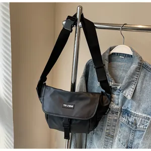 Detail view of water-resistant black crossbody bag with flap buckle and brand logo