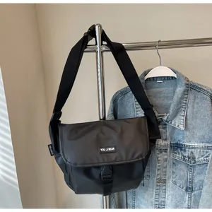 Close-up of waterproof matte black messenger bag featuring buckle closure and brand tag
