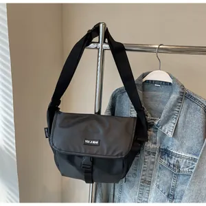 Close-up of black water-resistant messenger bag with adjustable strap and brand logo