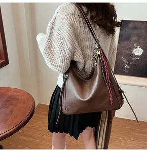 Detail of vintage brown PU tote bag with side zipper and decorative key-shaped gold pendant