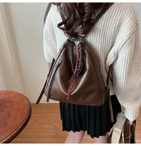 Detail of dark brown faux leather backpack with triangular design and woven ornament