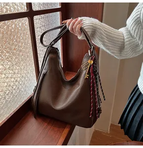 Detailed texture of dark brown PU leather tote bag with golden key and woven charm