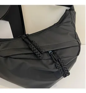 Detail of smooth black nylon crossbody bag featuring heavy duty zipper and paracord puller