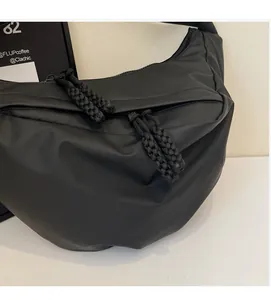 Detail of black nylon crescent bag featuring a black and white braided rope zipper pull