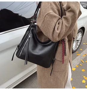 Close-up of black PU leather hobo bag featuring side tassel zipper and grainy texture
