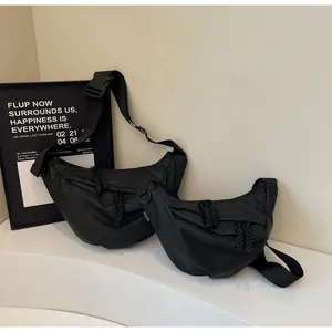 Close-up of black nylon crossbody bags showing dual-zip pulls and plastic buckle