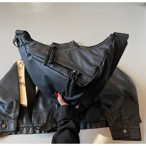 Detail of black nylon half-moon crossbody bag with woven zipper pull and adjustable strap