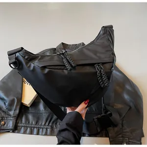 Detail of black crescent crossbody bag with braided rope zippers and adjustable nylon strap