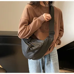Detail of a black crescent nylon crossbody bag with adjustable wide strap and zipper cord