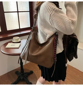 Brown vintage PU leather tote bag with tassel zipper detail shown in a cozy lifestyle setting