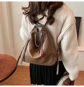 Close-up of vintage brown PU leather tote with decorative tassels and woven rope handle