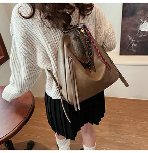 Detailed side view of deep brown large tote bag with fringe tassels and woven straps