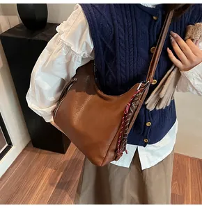 Detail of brown PU leather hobo bag featuring silver zipper and woven tassel accessory