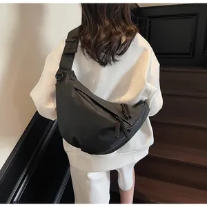 Rear view of a model wearing a black nylon crescent crossbody bag with an adjustable strap