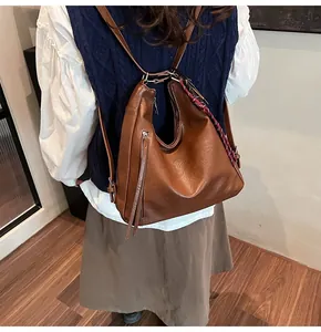 Brown vintage PU leather tote bag shown as a backpack with tassel zippers on a model