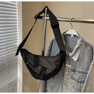 Detail of black crescent crossbody bag with adjustable strap and side knot accents