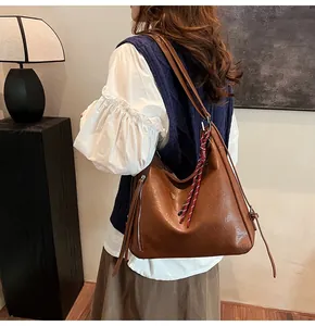 Detail shot of a brown vintage PU leather tote bag with decorative side zipper and woven charm