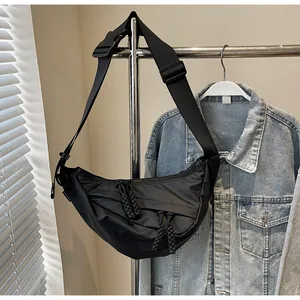 Detail of black nylon crescent crossbody bag featuring woven rope zippers and wide strap