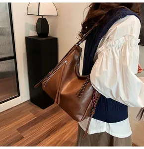 Detail of a brown PU leather hobo tote bag featuring woven rope and long tassel accents