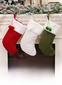 Detail of three knitted Christmas stockings with plush cuffs hanging on a white fireplace