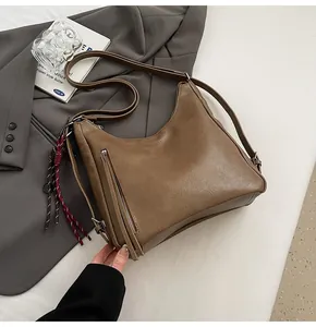 Close-up detail of vintage brown PU tote bag with diagonal zipper and woven charm