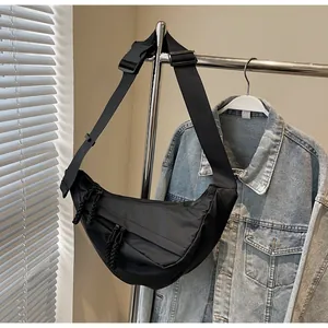 Close-up of black nylon crescent crossbody bag with adjustable strap and plastic buckle