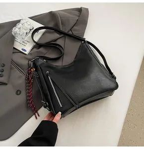 Detailed close-up of a black PU leather tote featuring a zipper with long tassel and side charms