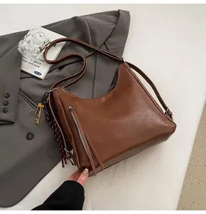 Detail of brown PU leather tote with vertical zipper pocket and key charm pendant