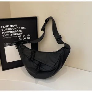 Detail of a black nylon crescent crossbody bag with adjustable strap and dual zip pulls