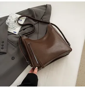 Detailed macro view of deep brown PU leather crossbody bag with front zipper pocket and strap