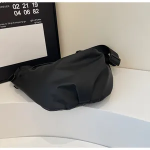 Detail of minimalist black canvas crossbody bag with adjustable strap and textured pleats