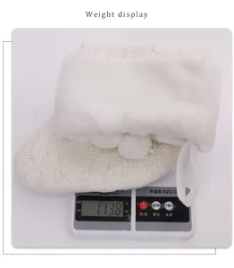 Detailed view of white knitted Christmas stocking weighing 113.8g on a digital scale