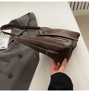 Detail view of smooth brown PU leather shoulder bag with silver zipper and adjustable strap