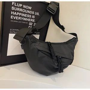 Detail of black nylon crescent crossbody bag with large buckle and fashion label
