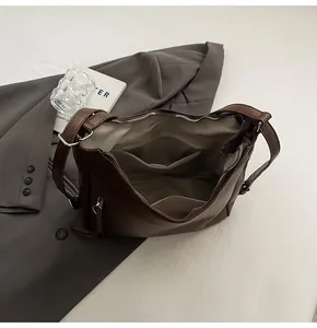 Detail view of dark brown PU tote bag with inner zipper pocket and smooth silver zip closure