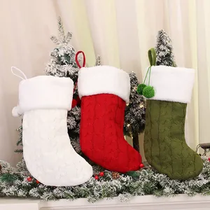 Three knitted Christmas stockings in red, white and green with faux fur trim and pom-poms