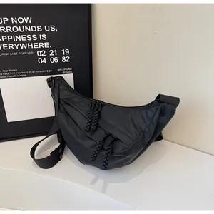 Detail of minimalist black nylon crescent bag featuring dual zippers with cord pullers