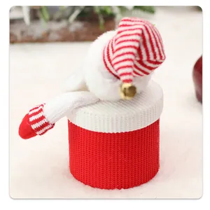 Detail of red and white knitted Christmas gift box with plush ball and golden bell accent