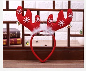 Detail of red antler headband featuring white snowflakes, golden bells, and white feathers