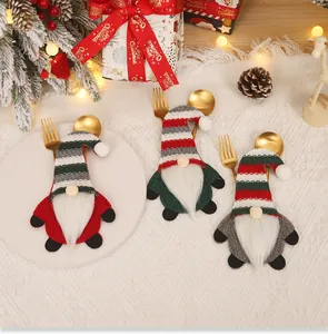 Three festive gnome cutlery holders featuring knitted hats and beards on a Christmas table