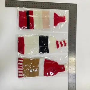 Flat lay of festive knitted wine bottle covers with stripe patterns and measuring scale
