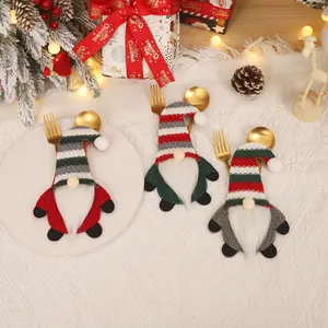 Three Christmas gnome cutlery holders with striped hats and white beards on table