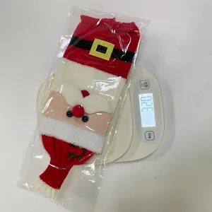 Macro detail of knitted Santa wine bottle cover showing red wool texture and golden buckle