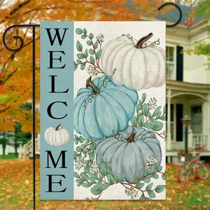 Outdoor garden flag detail showing three pumpkins and Welcome text in autumn courtyard