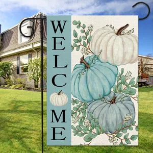 Close-up of harvest garden flag with pumpkins and welcome text in a backyard setting