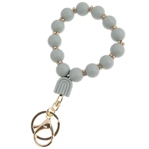 Detail showing grey silicone beaded wristlet with rainbow pendant and golden lobster clasp