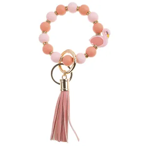 Detail of pink silicone bead bracelet keychain with flamingo charm and faux leather tassel