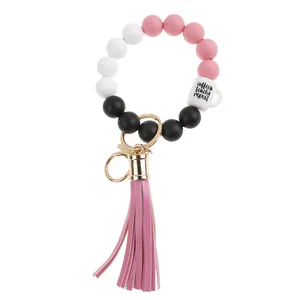 Detail of pink silicone bead bracelet with fringe and coffee teach repeat charm