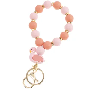 Detail of pink silicone beaded keychain bracelet with golden spacer rings and flamingo charm