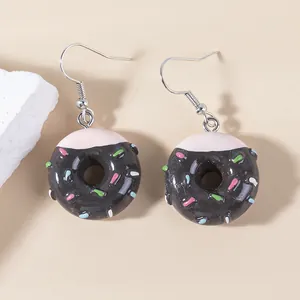 Macro detail of chocolate donut earrings with pink glaze and colorful sprinkles